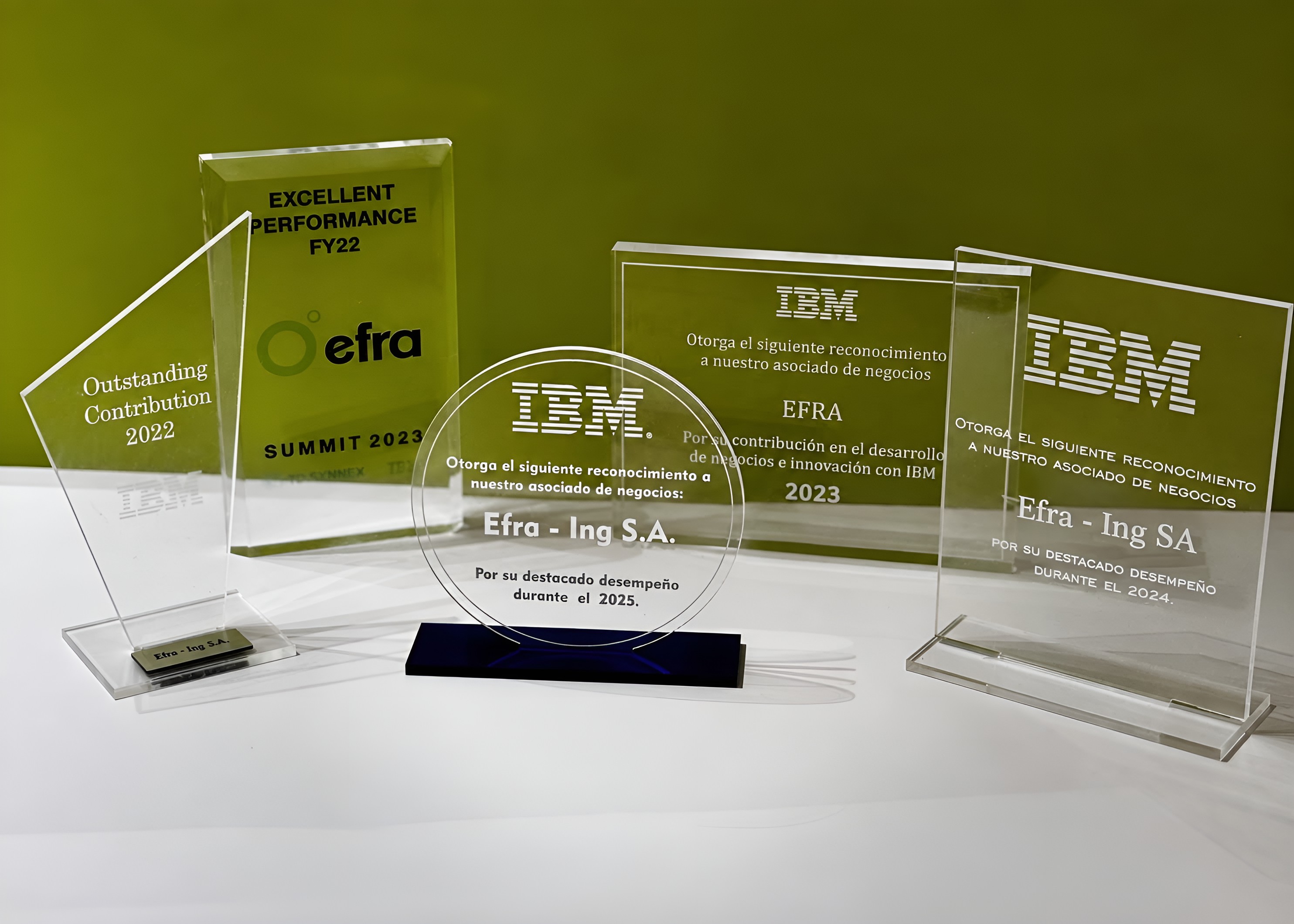 Cinco premios de IBM y TD SYNNEX recibidos por Efra entre 2022 y 2025, sobre una mesa blanca frente a un panel verde